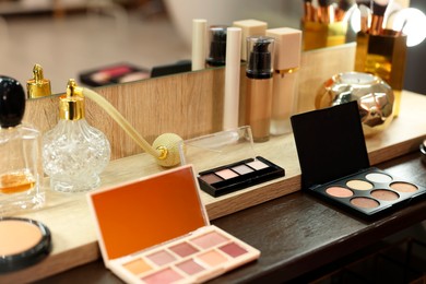 Photo of Makeup room. Cosmetic products and perfumes on wooden dressing table indoors