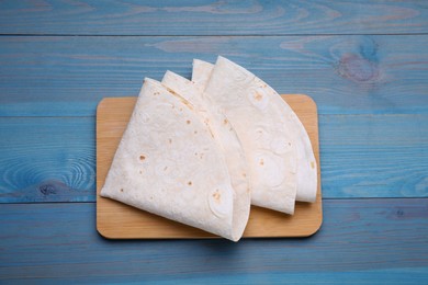 Delicious folded Armenian lavash on light blue wooden table, top view