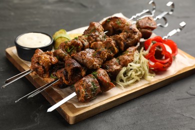Photo of Metal skewers with delicious meat and vegetables served on black table
