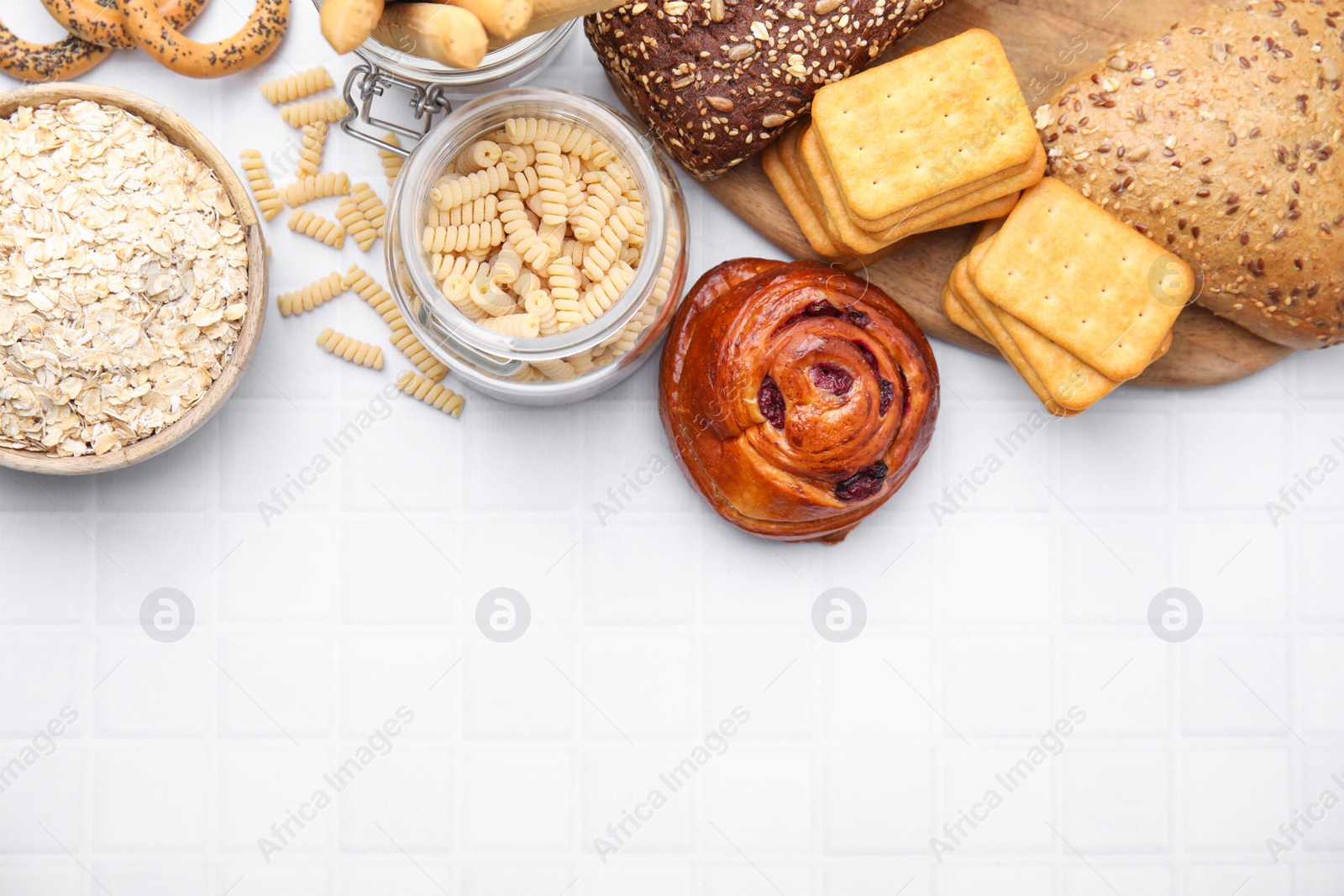Photo of Different gluten free products on white tiled table, flat lay. Space for text