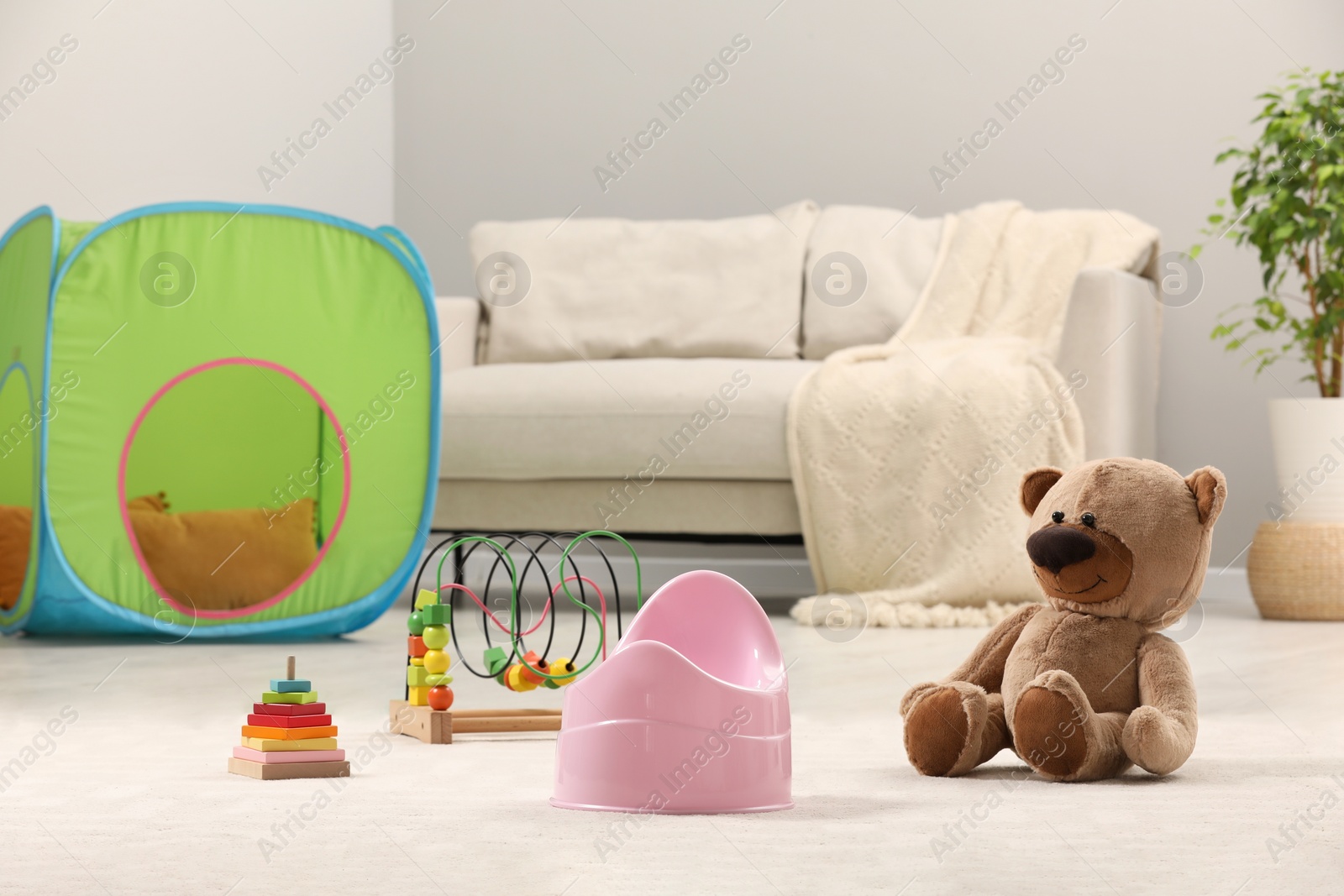 Photo of Pink baby potty and toys on floor at home. Toilet training