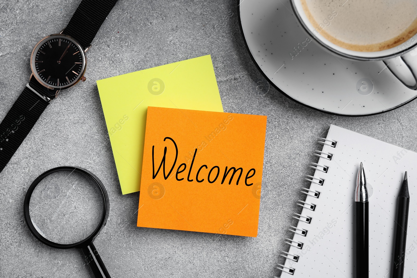 Image of Paper note with word Welcome on grey table. Office desk with stationery and coffee, flat lay