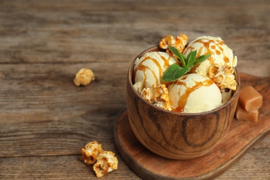 Photo of Delicious ice cream with caramel popcorn and sauce served on table. Space for text