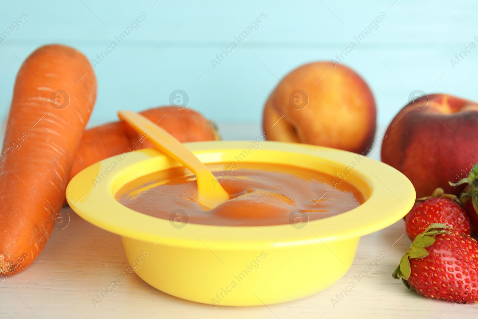 Photo of Baby food in bowl and fresh ingredients on white wooden table