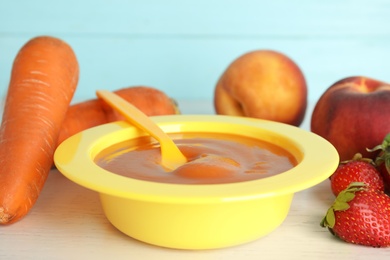 Photo of Baby food in bowl and fresh ingredients on white wooden table