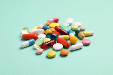 Pile of many different pills on turquoise background.