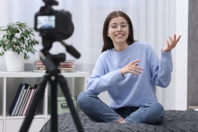 Photo of Smiling teenage blogger explaining something while streaming at home