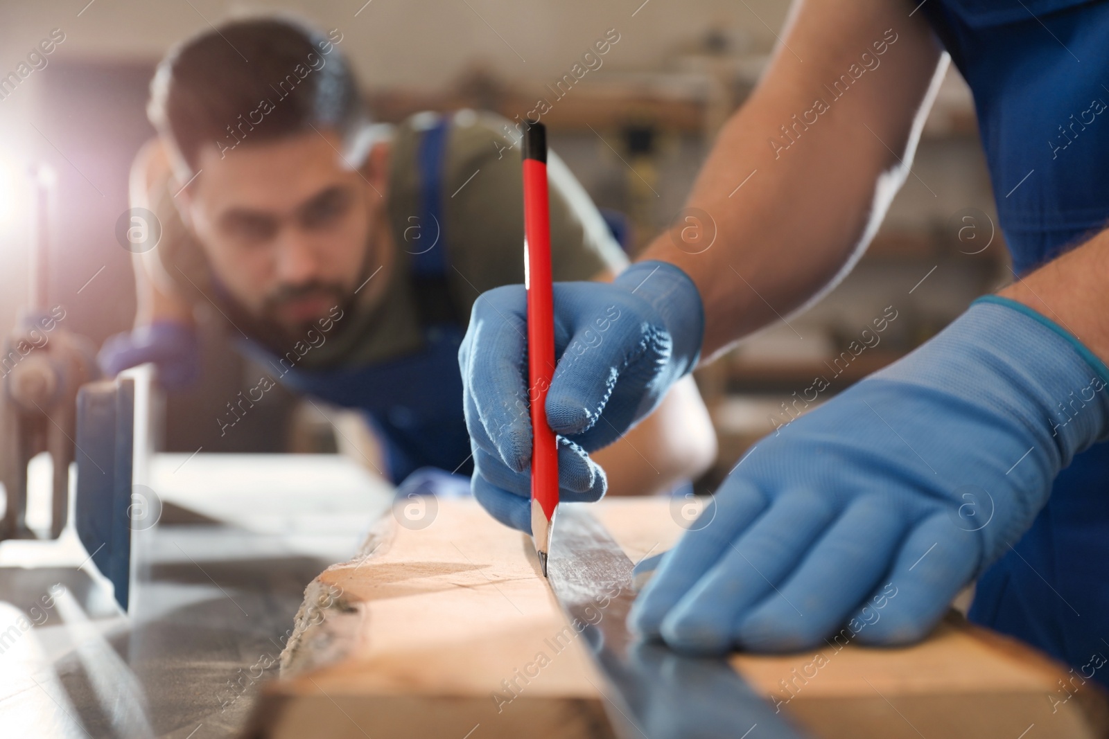 Photo of Professional carpenter making mark on wooden board in workshop, closeup