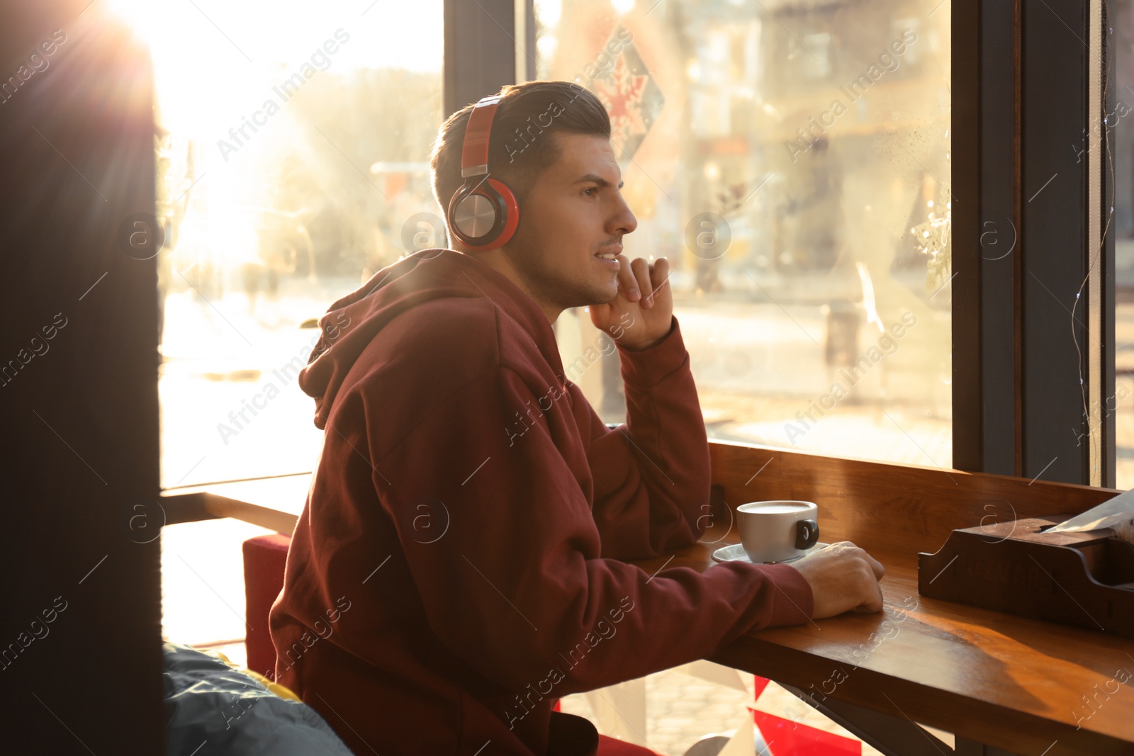 Photo of Man listening to audiobook at table in cafe