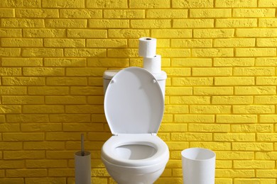 Photo of Simple bathroom interior with toilet bowl near yellow brick wall indoors. Home design