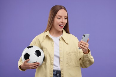 Emotional sports fan with ball and smartphone on purple background