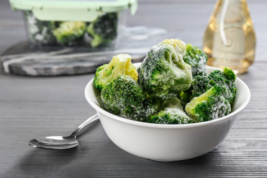 Photo of Frozen broccoli on light grey wooden table, closeup. Vegetable preservation