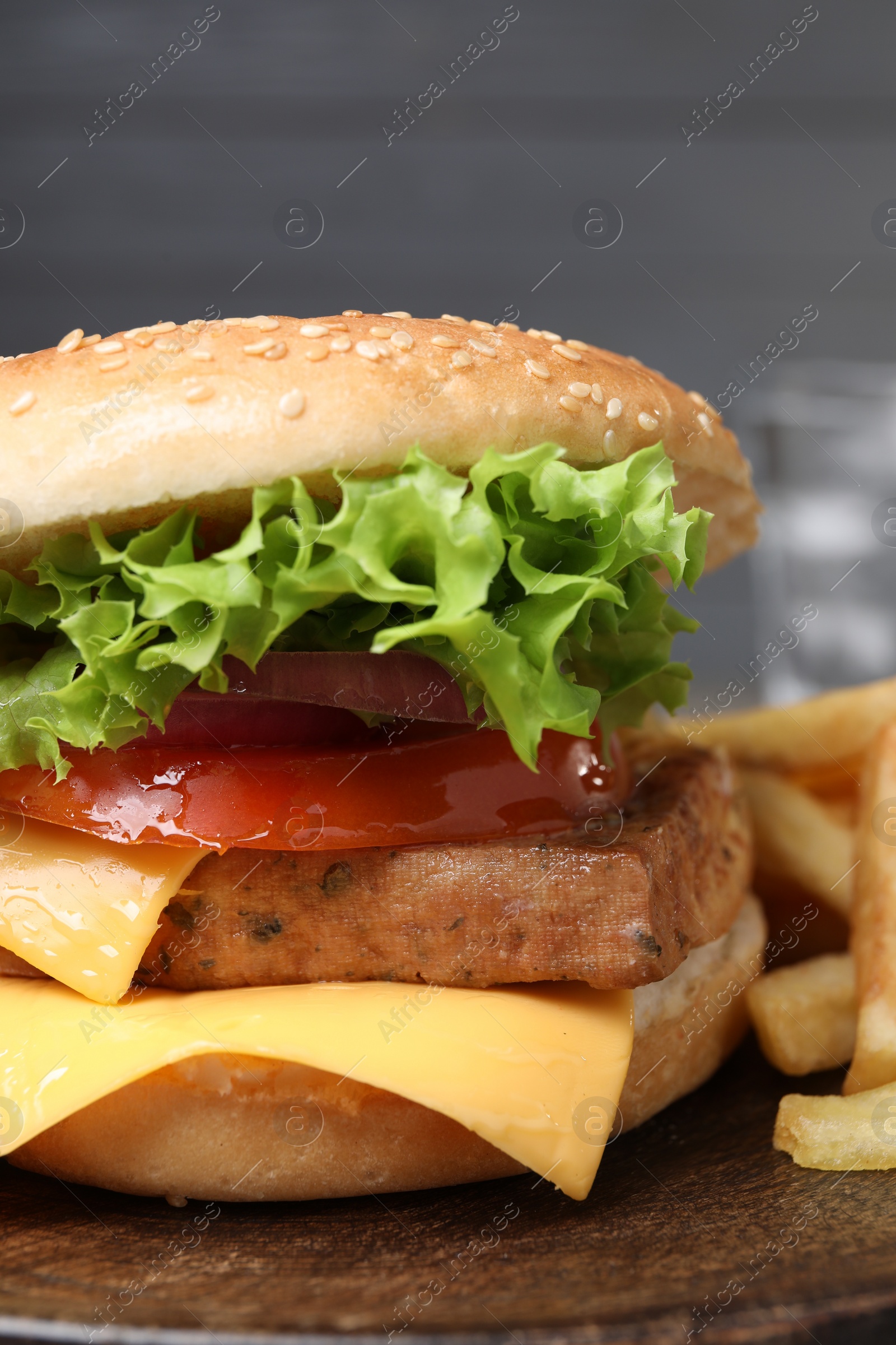 Photo of Delicious burger with tofu and fresh vegetables on wooden table, closeup