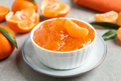 Photo of Delicious tangerine jam on light grey table, closeup