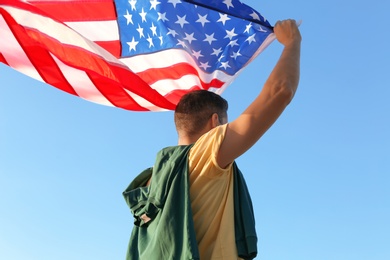 Photo of Man with American flag against blue sky