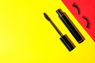 Photo of Black mascara and fake eyelashes on color background, flat lay with space for text. Makeup product