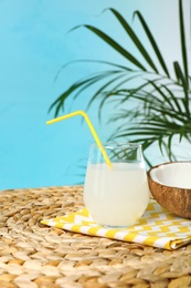 Composition with glass of coconut water on wicker table against blue background