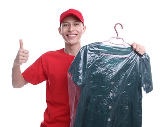 Photo of Dry-cleaning delivery. Happy courier holding dress in plastic bag and showing thumbs up on white background