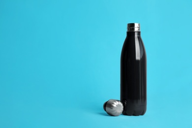 Photo of Stylish thermo bottle on light blue background, space for text