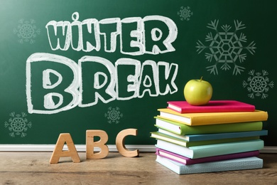 Image of Text Winter Break on school chalkboard near table with books, letters and apple