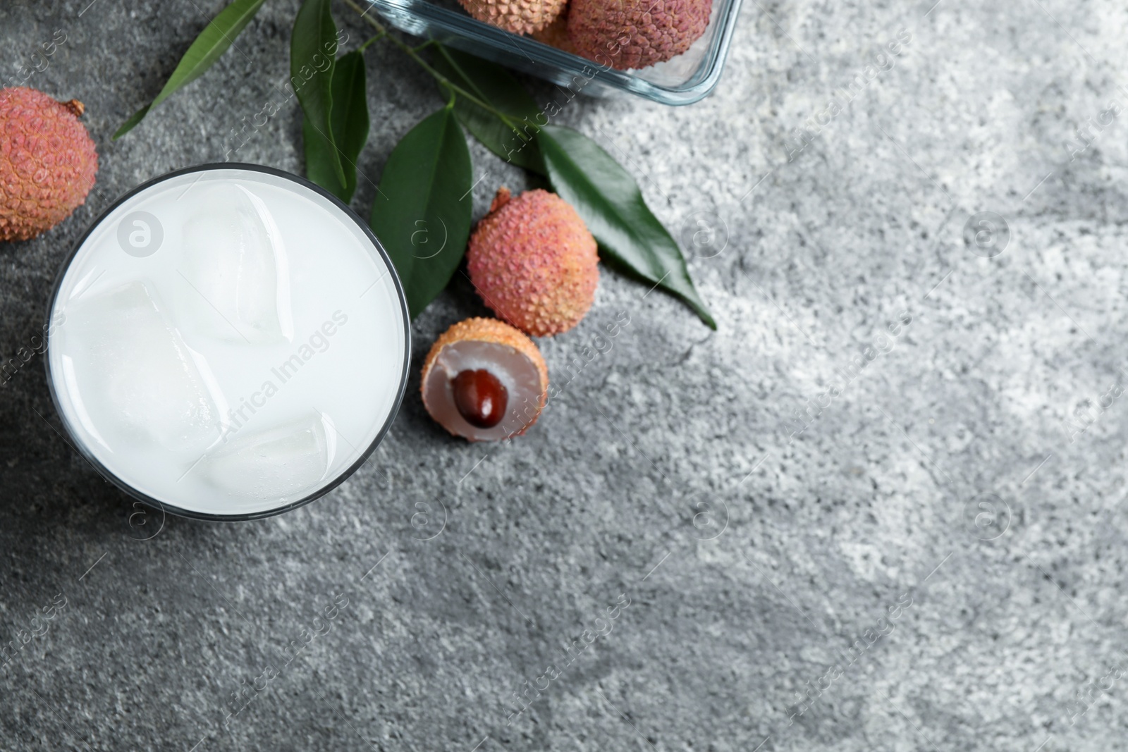 Photo of Fresh lychee juice and fruits on grey table, flat lay. Space for text