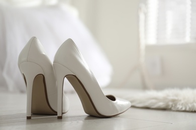 Photo of White wedding shoes on floor in room