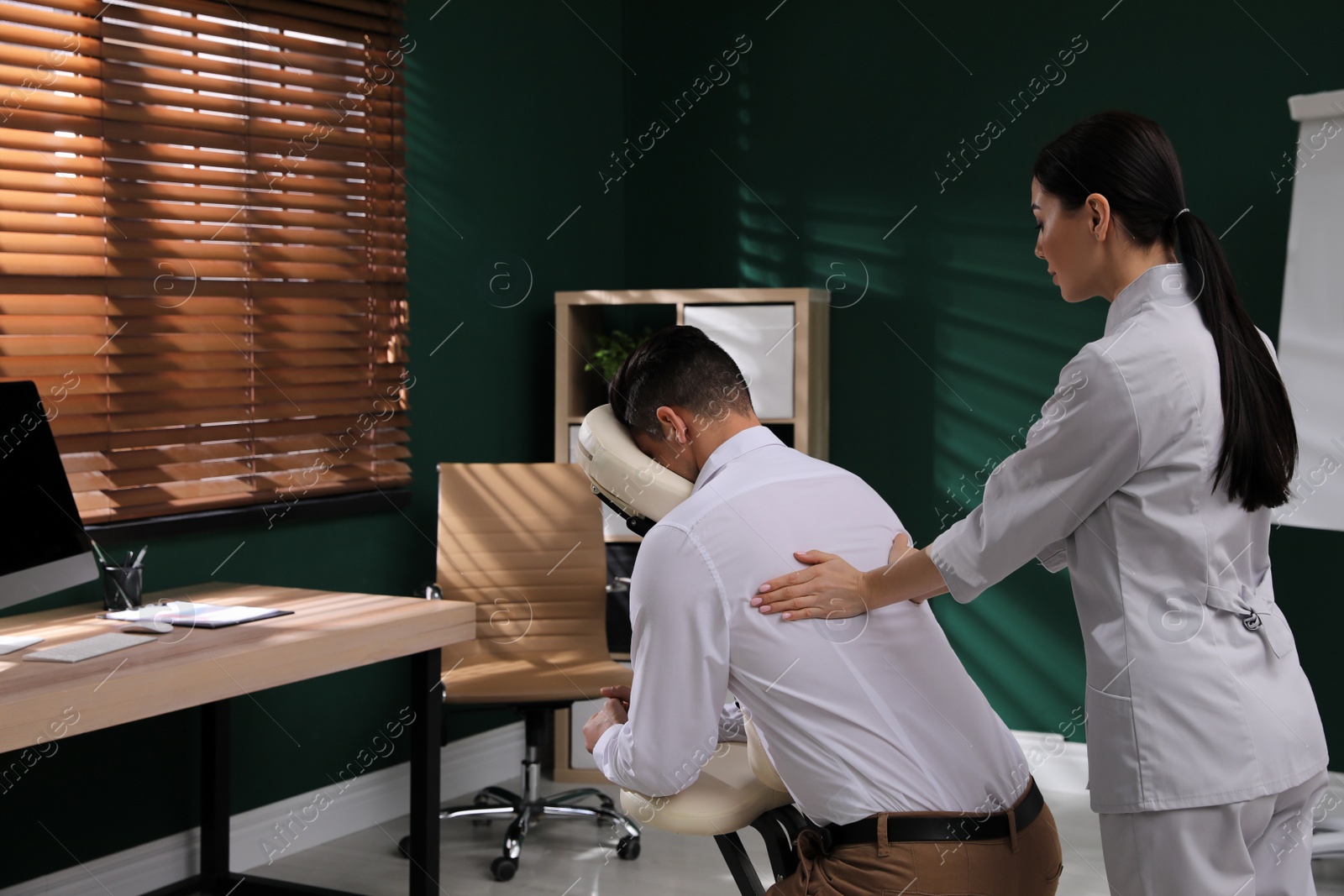 Photo of Man receiving massage in modern chair indoors