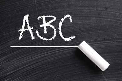 Image of Piece of white chalk and letters ABC written on blackboard, top view
