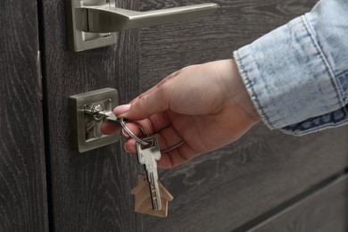 Photo of Woman unlocking door with key, closeup view