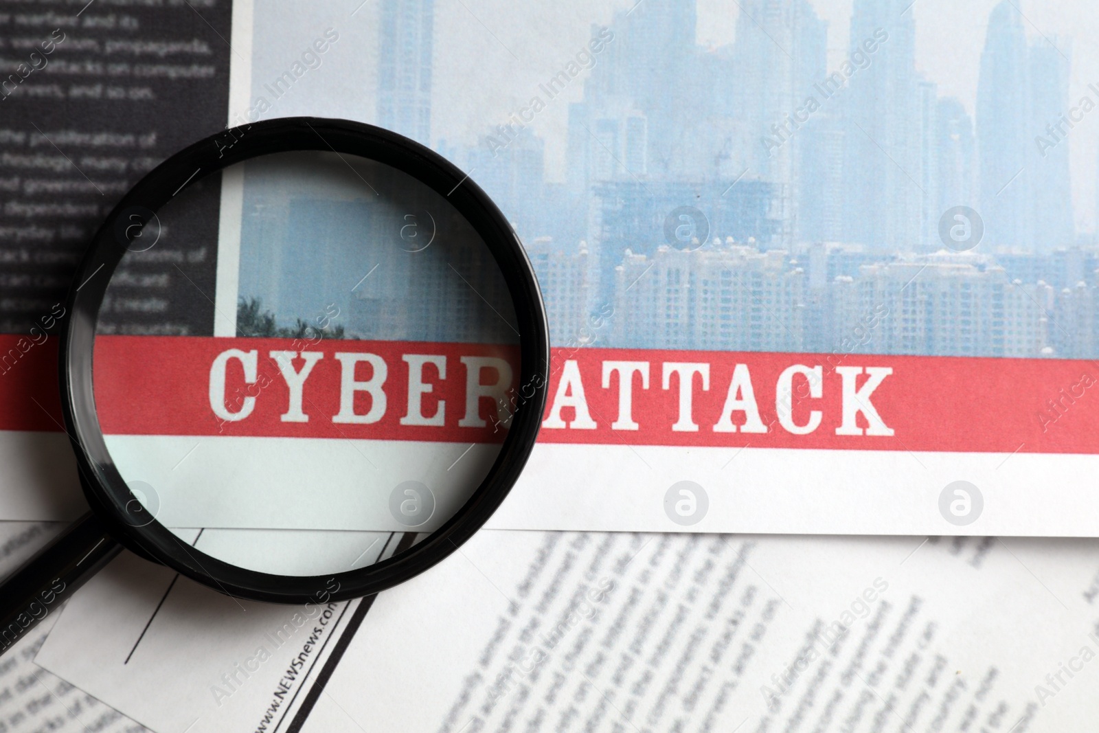 Photo of Newspaper with headline CYBER ATTACK and magnifying glass, top view