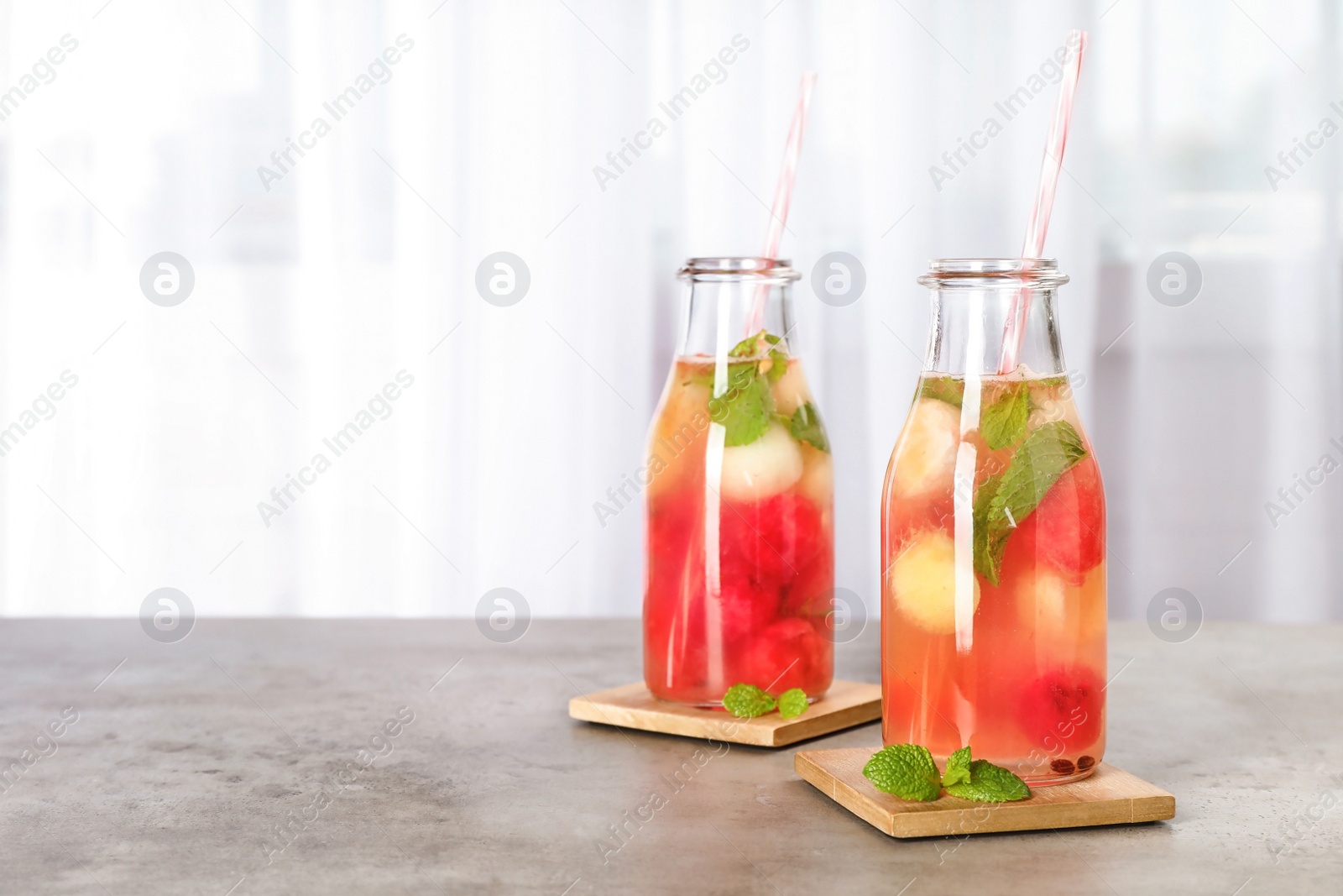 Photo of Bottles with tasty watermelon and melon ball drink on table. Space for text