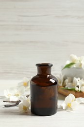 Photo of Jasmine essential oil and fresh flowers on white wooden table