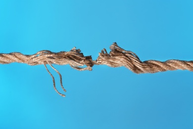 Frayed rope breaking on color background, closeup