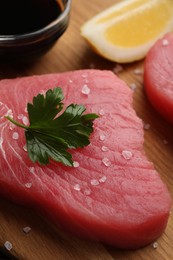 Fresh raw tuna fillet with sea salt and parsley on wooden table, closeup