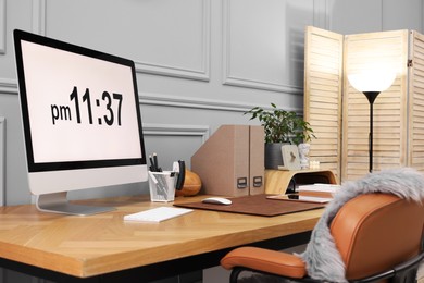 Photo of Stylish workplace with computer, houseplant and stationery on wooden desk near grey wall at home