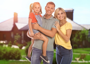 Image of Happy family standing in front of their house on sunny day 