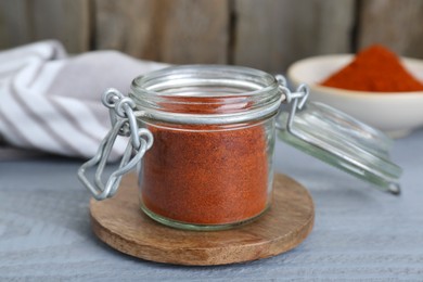 Jar with aromatic paprika powder on grey wooden table