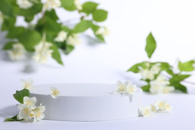 Photo of Presentation of product. Podium and beautiful jasmine flowers on white background, closeup