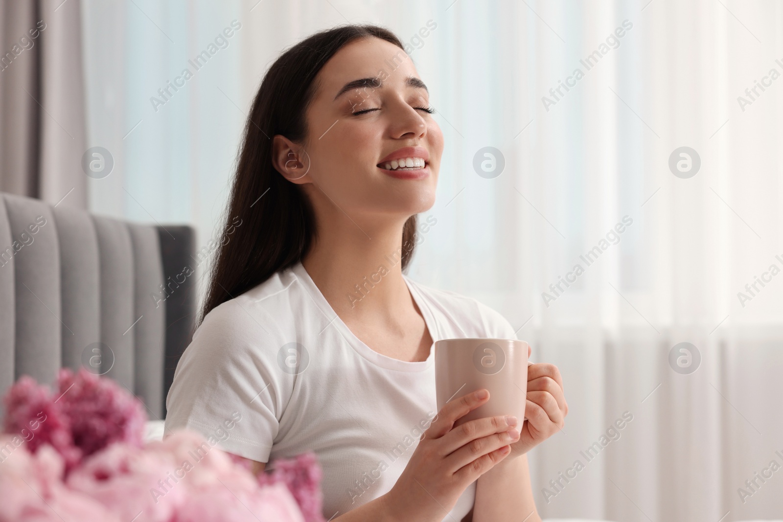 Photo of Happy woman with cup of drink at home, space for text. Lazy morning