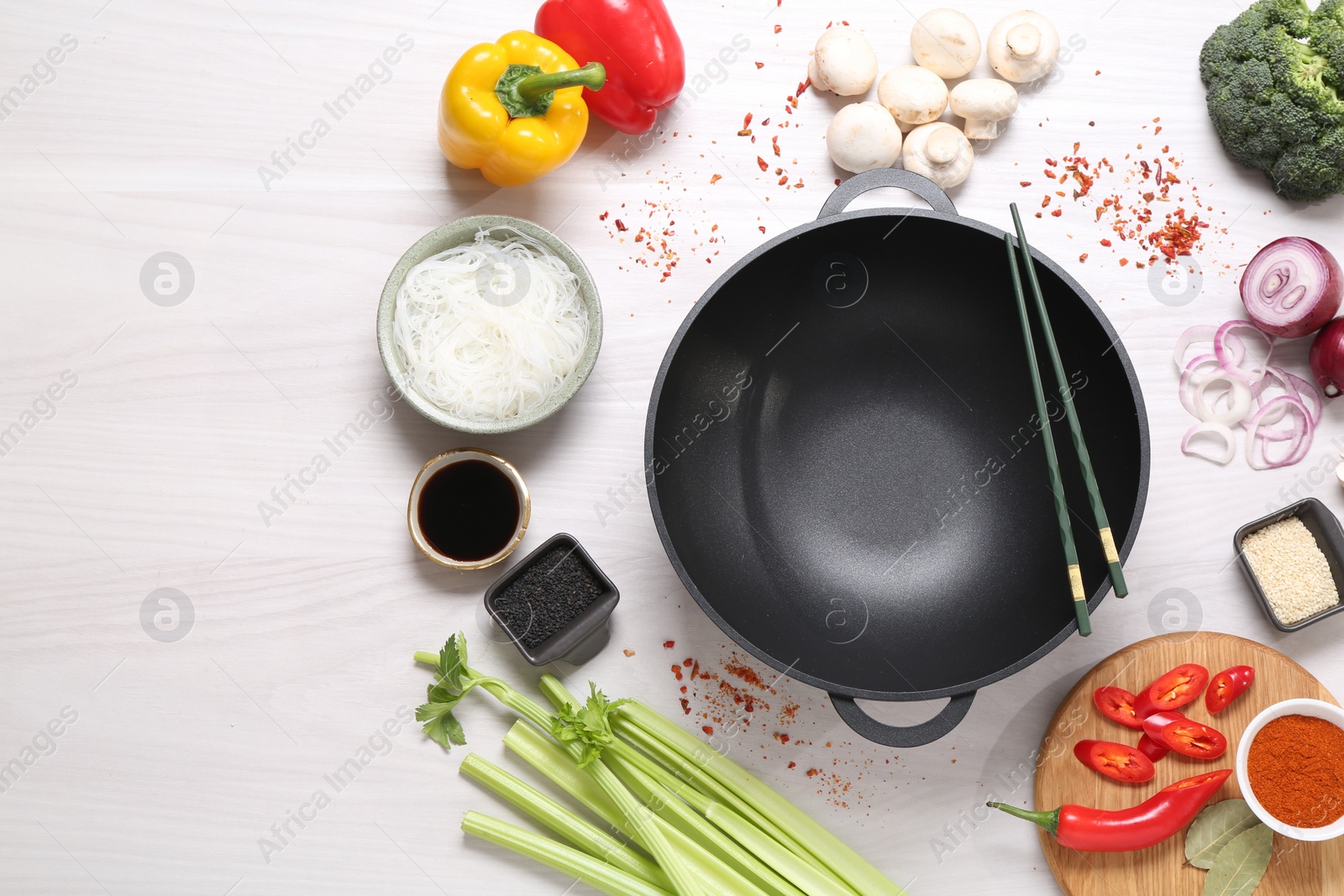 Photo of Wok, chopsticks and different products on white wooden table, flat lay. Space for text