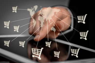 Woman using tablet for online purchases on gray background, closeup. Illustration of world map and shopping cart icons above device screen