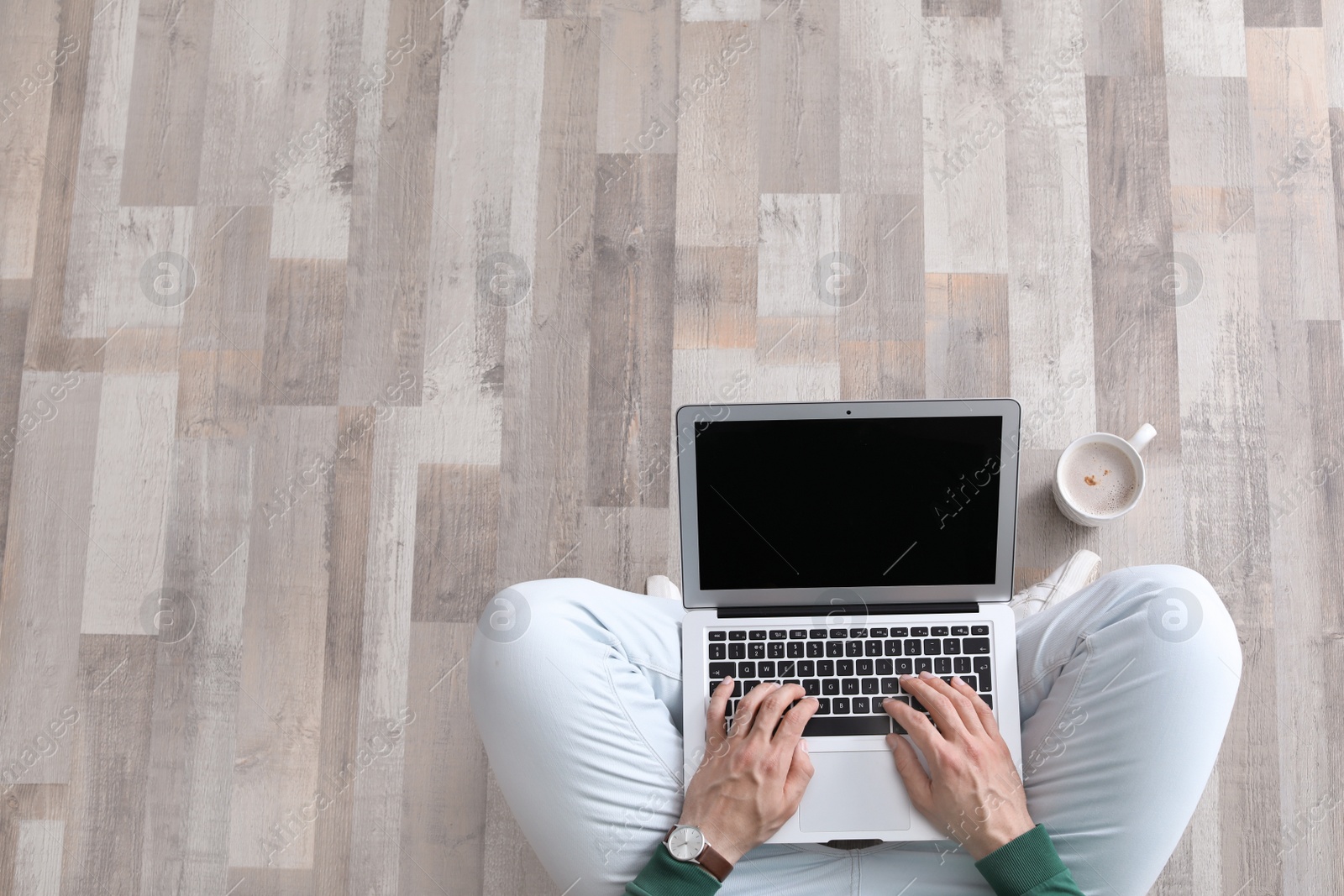 Photo of Young man with laptop sitting on floor, top view