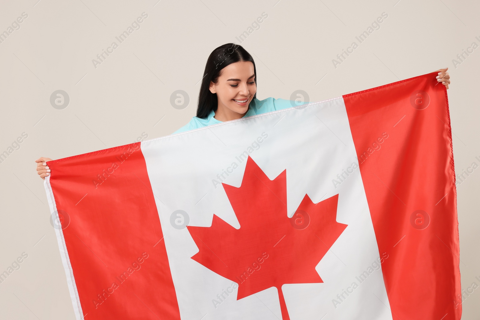 Photo of Happy young woman with flag of Canada on beige background