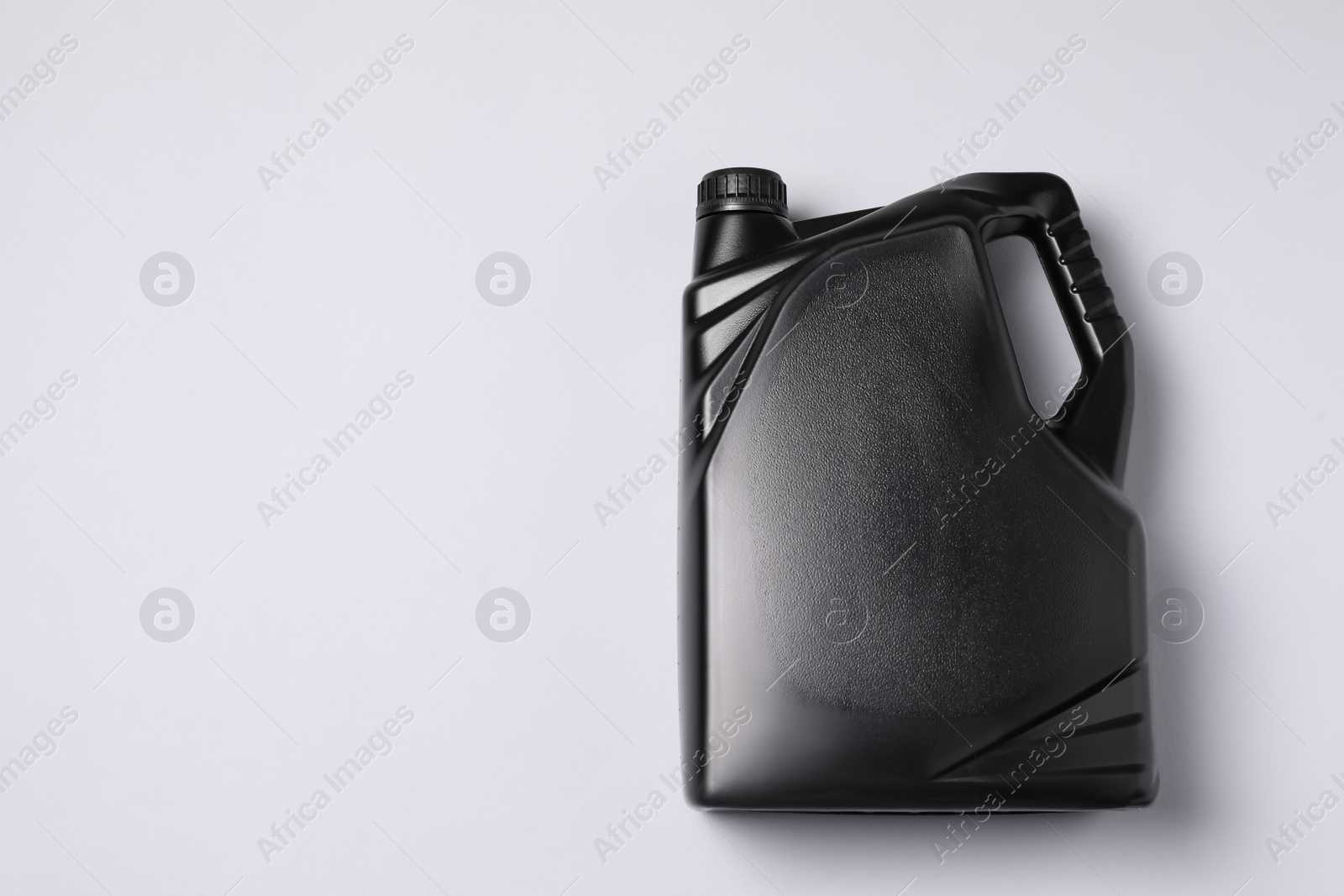 Photo of Motor oil in black canister on light background, top view. Space for text