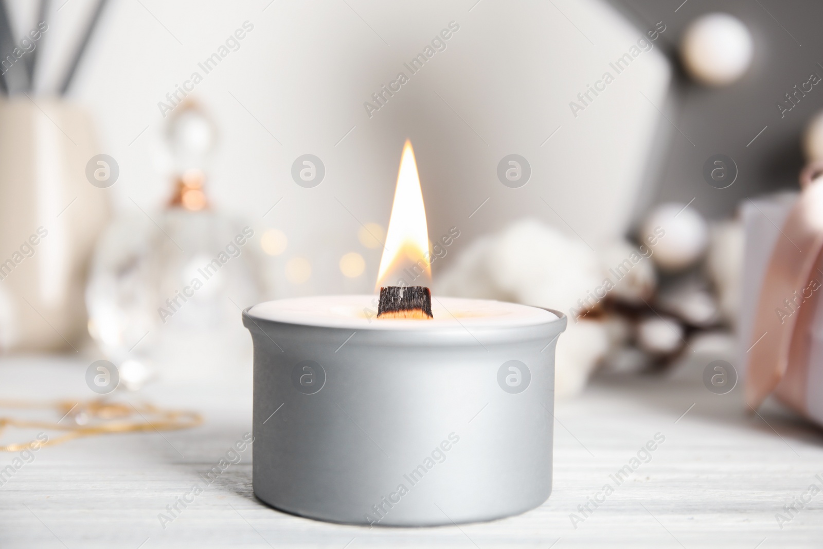 Photo of Beautiful burning candle on white wooden table, closeup