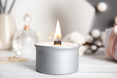 Photo of Beautiful burning candle on white wooden table, closeup