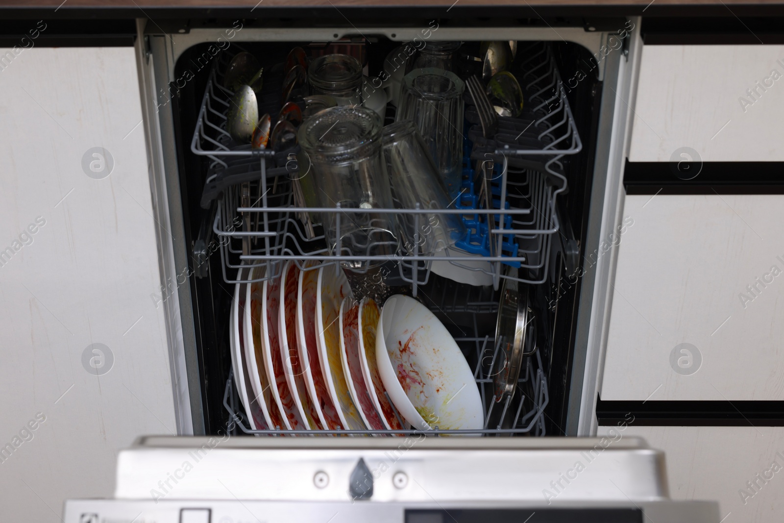 Photo of Open modern dishwasher with dirty tableware in kitchen