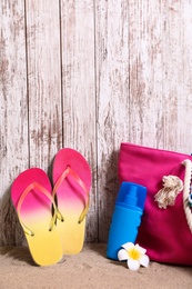 Photo of Composition with stylish summer beach accessories on sand near wooden wall. Space for text