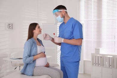 Photo of Doctor taking nasal smear of pregnant woman for coronavirus test in clinic