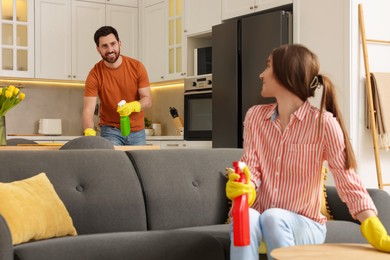 Photo of Spring cleaning. Lovely couple tidying up living room and kitchen together